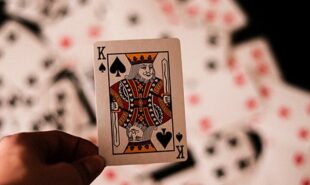 King of Spades card held over a deck of cards