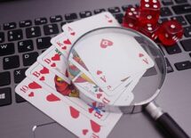 Laptop with playing cards, dice and magnifying glass. Concept of online gambling
