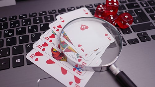 Laptop with playing cards, dice and magnifying glass. Concept of online gambling