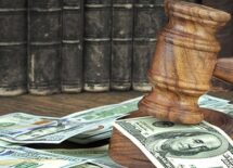 Judges Gavel And Scattered Money Heap On Wooden Table Close Up