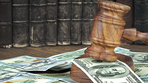 Judges Gavel And Scattered Money Heap On Wooden Table Close Up