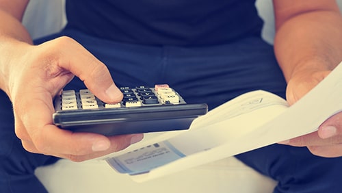 closeup of a man checking payroll with a calculator