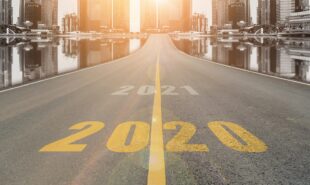 The number 2020 symbol represents the new year on the road heading to the city with beautiful skyscrapers background,