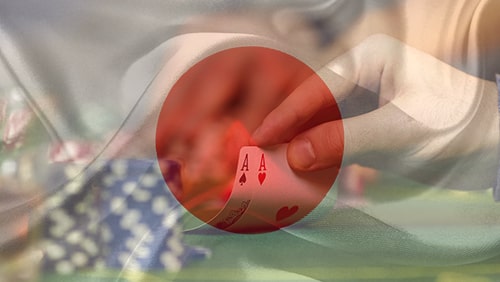 Japanese flag over a picture of a hand playing poker and showing 2 aces. Concept of Japanese Casino