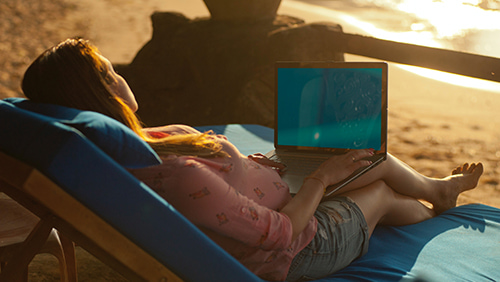 A girl holding a laptop while on the beach