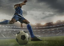 Save Download Preview Professional football or soccer player in action on stadium with flashlights, kicking ball for winning goal