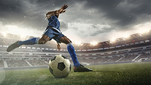   Save Download Preview Professional football or soccer player in action on stadium with flashlights, kicking ball for winning goal