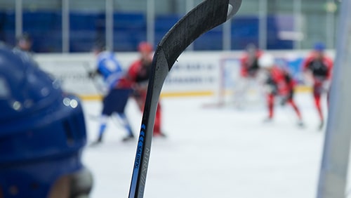 Close up of a hockey stick against a hockey game background