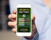 Hand holding a mobile phone with a sports betting app open