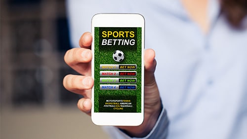 Hand holding a mobile phone with a sports betting app open