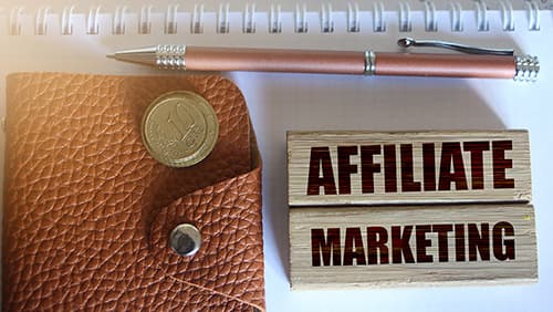 Affiliate marketing typed on wooden blocks, wallet, coins, pen. Business concept