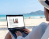 Mockup image of a woman using and typing on laptop computer in the beach