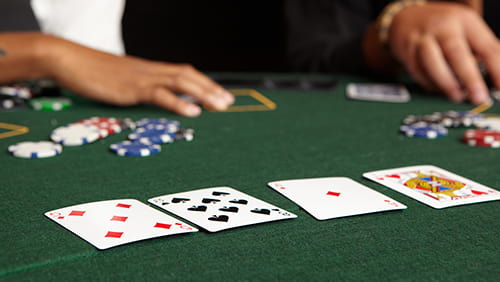 Playing cards chips and players gambling around a green felt poker table