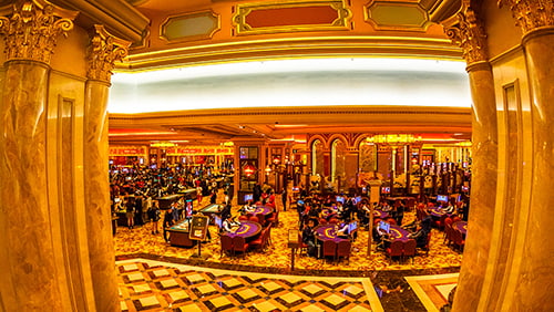 Aerial view of black jack tables and gamblers inside of a Casino in Macau