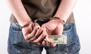 A man handcuffed while holding money