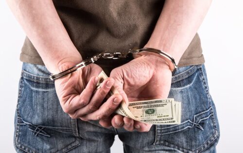 A man handcuffed while holding money