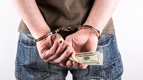 A man handcuffed while holding money