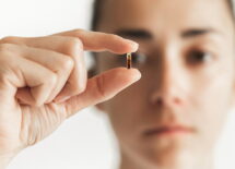 Person holding in fingers micro chip for implantation with defocused face on background