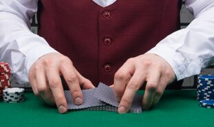the dealer's hands are holding a deck of cards and placing chips on the poker table
