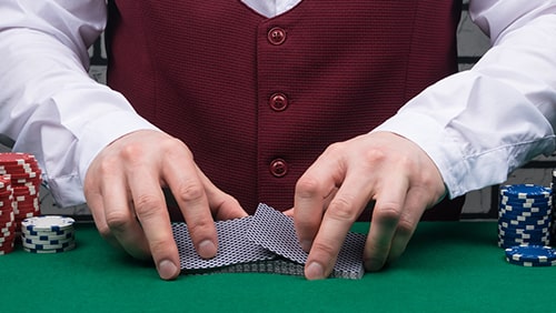 the dealer's hands are holding a deck of cards and placing chips on the poker table