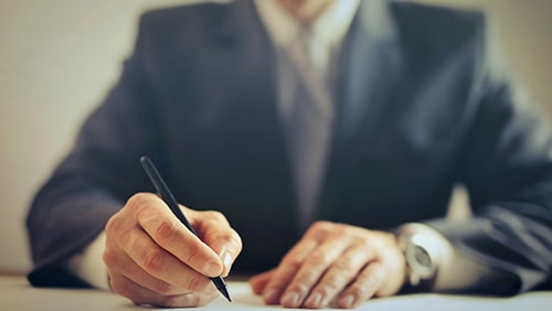 Zoomed photo of a male employee writing on a piece of paper