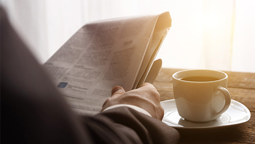 Businessman reading newspaper with coffee in the morning