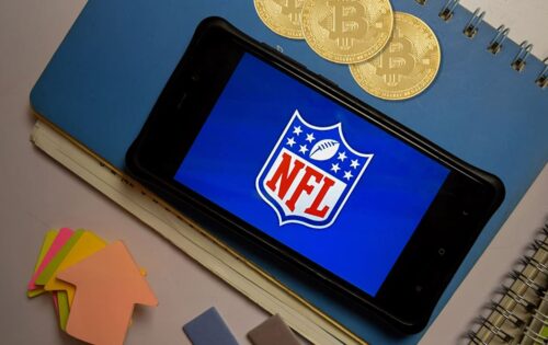 NFL logo on a mobile screen with bitcoins signifying digital currencies