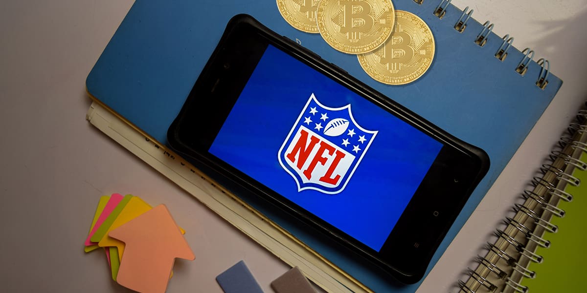 NFL logo on a mobile screen with bitcoins signifying digital currencies