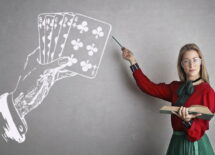 A teacher pointing a drawing of playing cards and a hand on a blackboard