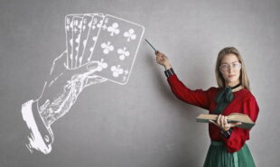 A teacher pointing a drawing of playing cards and a hand on a blackboard