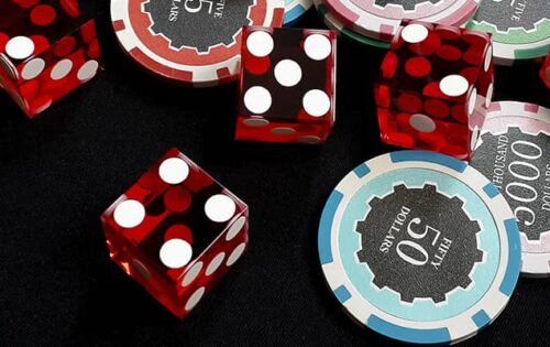 Five red dice and stacked of chips bet many value on black fabric Gambling devices and casino concept