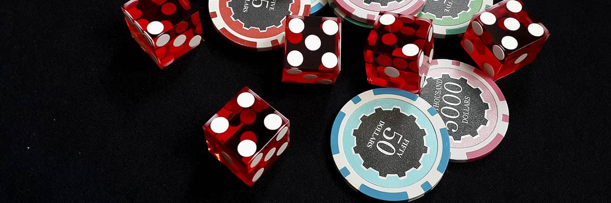 Five red dice and stacked of chips bet many value on black fabric Gambling devices and casino concept
