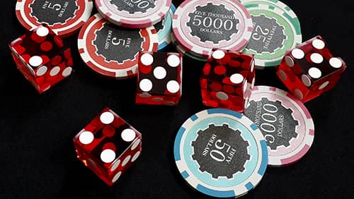 Five red dice and stacked of chips bet many value on black fabric Gambling devices and casino concept