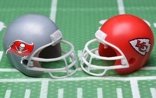 Helmets for the Tampa Bay Buccaneers, and Kansas City Chiefs, opponents in Super Bowl LV. on a green football field background