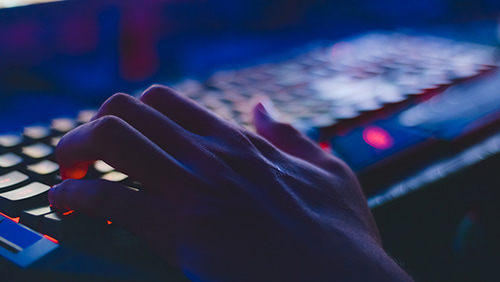 Photo of person typing on a gaming computer keyboard