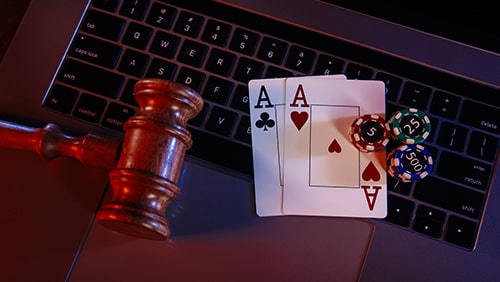 Wooden judge gavel and aces on keyboard of laptop