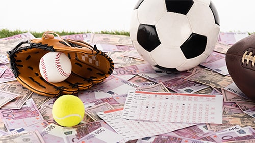 baseball glove and ball, soccer, tennis and rugby balls near betting lists on euro and dollar banknotes