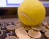 Coins and tennis ball over a laptop keyboard