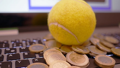 Coins and tennis ball over a laptop keyboard