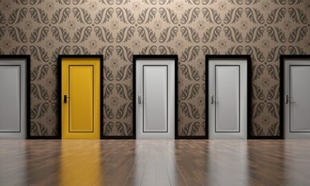 A row of closed white doors and one colored yellow