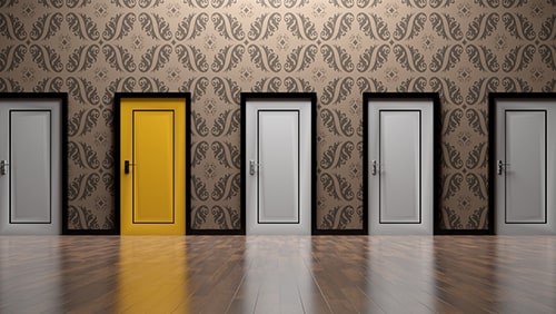 A row of closed white doors and one colored yellow