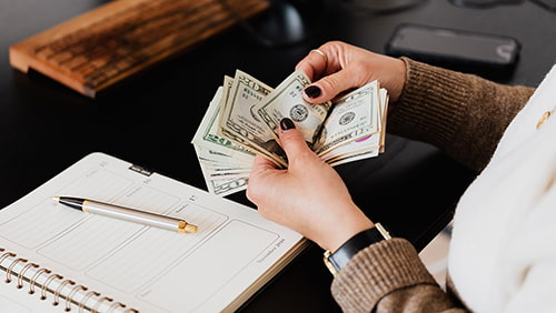 Woman counting money at modern office table