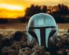 Mandalorian helmet on the ground with a sunset background