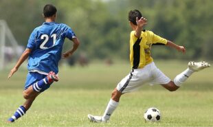 Two player in the soccer field kicking the ball