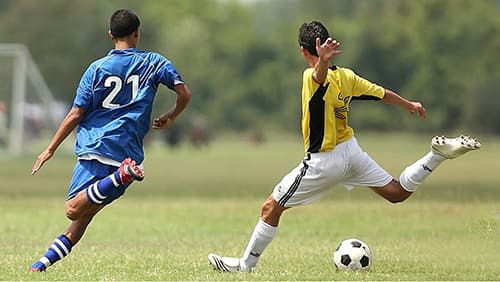 Two player in the soccer field kicking the ball